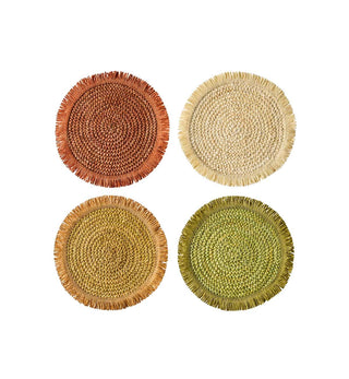 Four round woven placemats with frayed edges arranged in a 2x2 grid on a white background. The placemats are in four different earthy tones: terracotta red, natural straw beige, tan, and olive green.