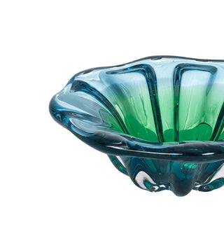 A close-up of a hand-blown glass bowl with a flared, scalloped rim, featuring a color gradient from deep teal-blue to vibrant green, set against a plain white background.