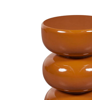 A close-up of a glossy terracotta-colored ceramic stack of three stacked bowls on a plain white background.