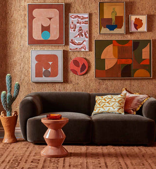 Living room with a brown couch, decorative pillows, and abstract wall art on a textured wall.